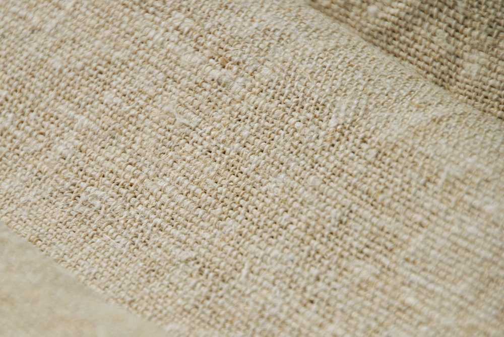 Macro detail of vintage hemp fabric showing the coarse, organic weave structure and natural beige fibers.