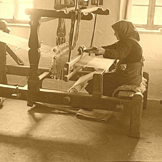 Historical sepia photograph of a Transylvanian woman weaving on a traditional wooden loom in a village home.
