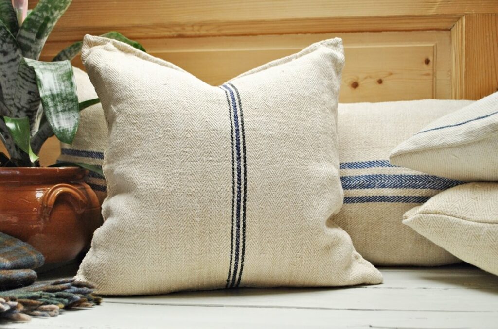 Authentic vintage grain sack pillows with striped patterns arranged on neutral farmhouse style sofa