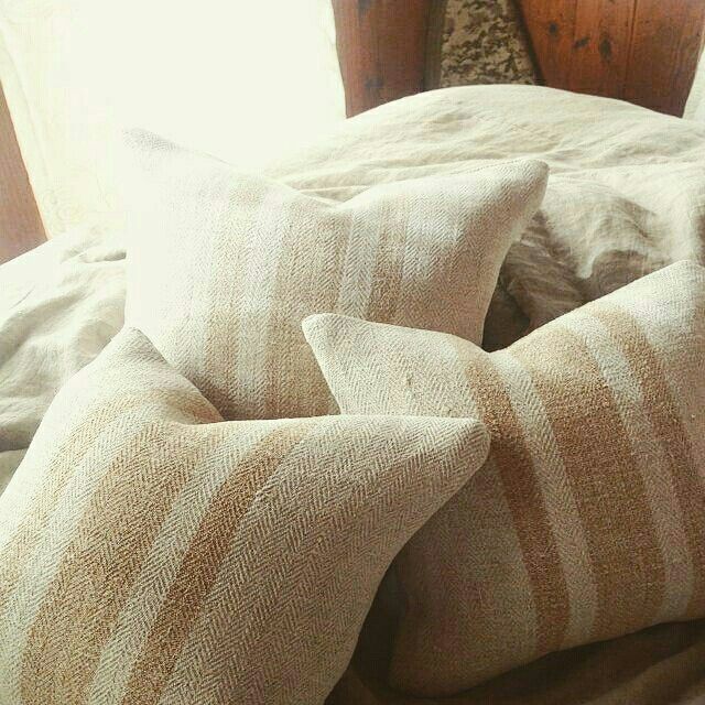 Group of antique grain sack pillows in warm natural light, oatmeal hemp herringbone texture, wabi-sabi interior styling