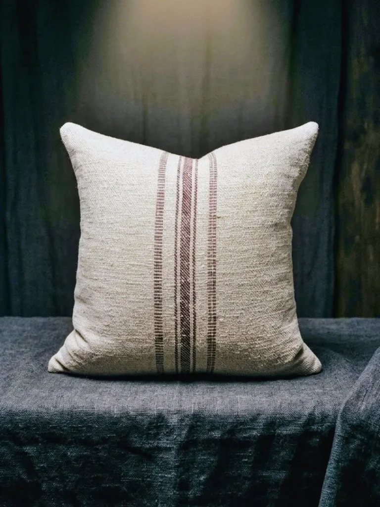 Antique Transylvanian grain sack cushion cover with burgundy stripe on dark charcoal linen, moody editorial photograph, one of a kind handwoven hemp textile circa 1900