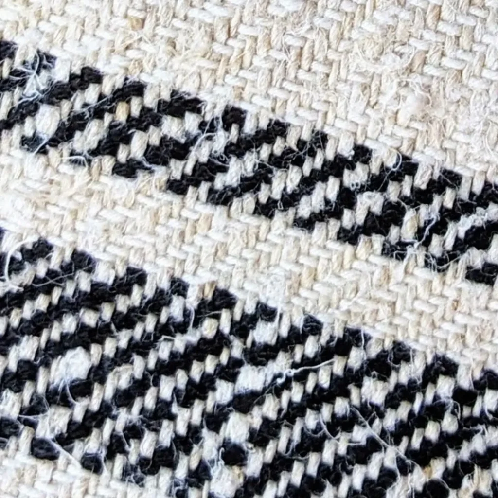 Extreme close-up of antique hand-woven Transylvanian hemp grain sack fabric showing uneven natural threads, stripe pattern and hand-stitching, circa 1900